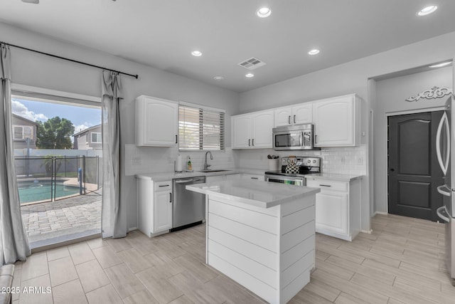 kitchen featuring white cabinets, stainless steel appliances, light countertops, and a sink