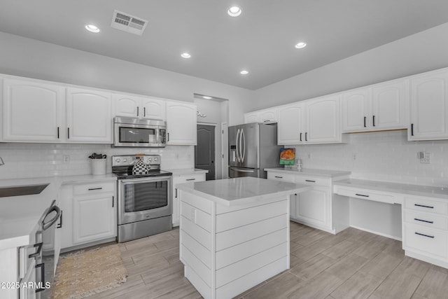 kitchen with visible vents, a sink, white cabinetry, appliances with stainless steel finishes, and light countertops