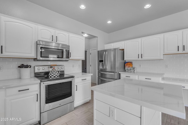 kitchen featuring tasteful backsplash, recessed lighting, appliances with stainless steel finishes, white cabinets, and wood tiled floor