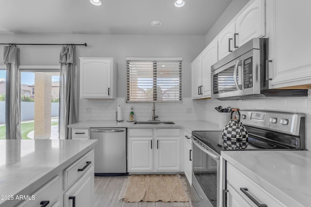 kitchen featuring decorative backsplash, stainless steel appliances, light countertops, and a sink