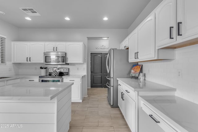 kitchen with light stone counters, visible vents, recessed lighting, white cabinets, and appliances with stainless steel finishes