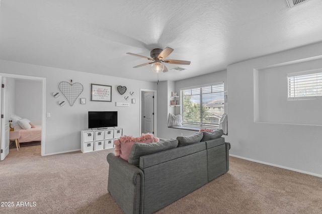 living area with plenty of natural light, carpet flooring, visible vents, and a ceiling fan