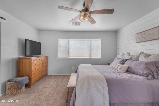 bedroom with baseboards, a ceiling fan, visible vents, and light carpet