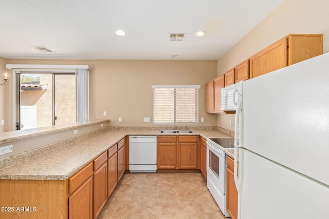 kitchen featuring visible vents, a healthy amount of sunlight, white appliances, and a sink