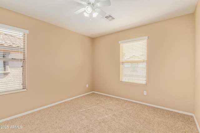 carpeted spare room featuring visible vents, baseboards, and a ceiling fan