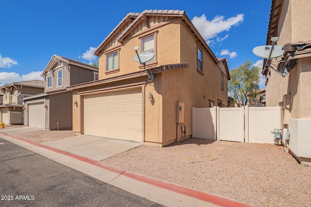 exterior space featuring fence, driveway, an attached garage, stucco siding, and a tile roof