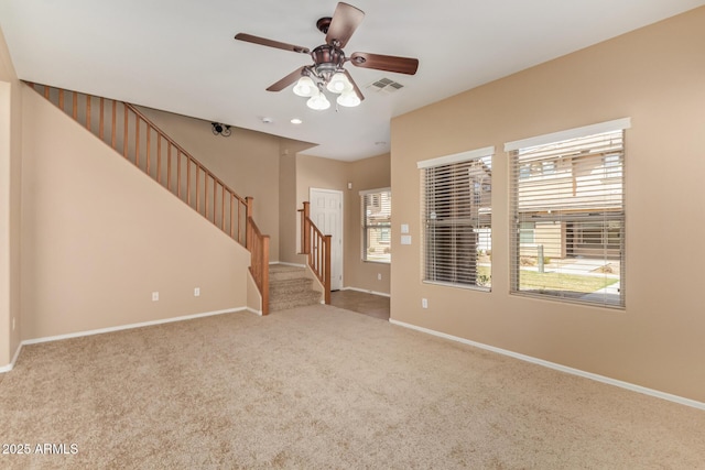 carpeted empty room featuring stairway, visible vents, and baseboards