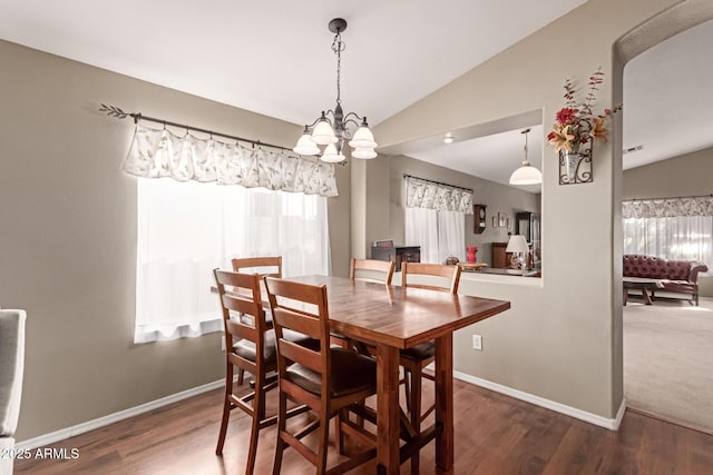 dining area with a chandelier, vaulted ceiling, and dark wood-type flooring