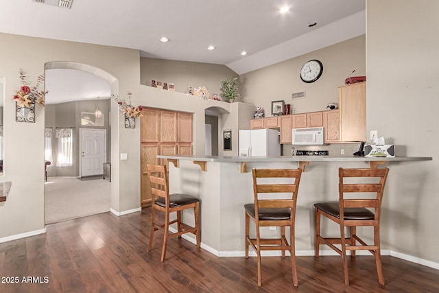 kitchen with vaulted ceiling, light brown cabinets, white appliances, kitchen peninsula, and a breakfast bar