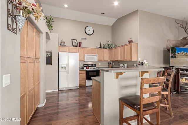 kitchen with white appliances, kitchen peninsula, a breakfast bar, dark wood-type flooring, and light brown cabinetry