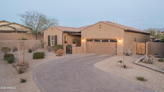 mediterranean / spanish-style home featuring a gate, fence, decorative driveway, and stucco siding