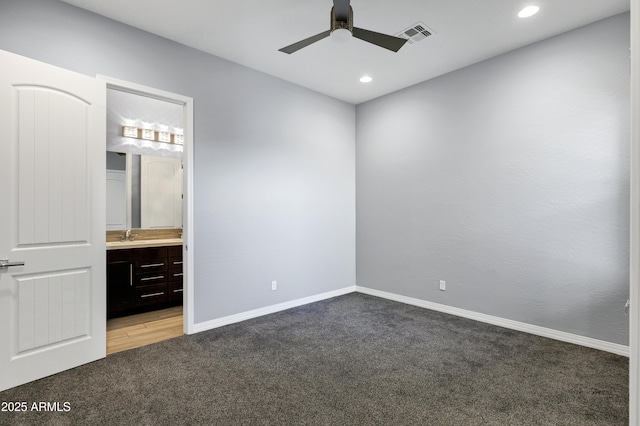 unfurnished bedroom with carpet, ensuite bathroom, and ceiling fan