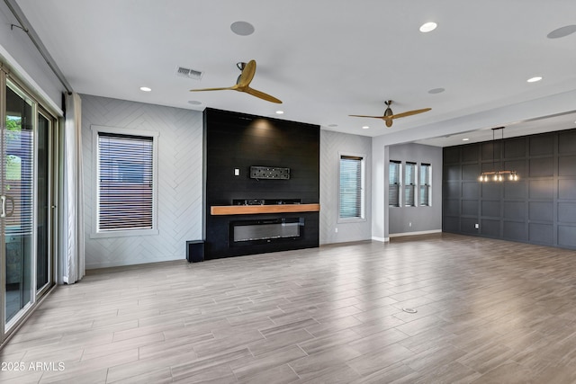 unfurnished living room with ceiling fan and a large fireplace