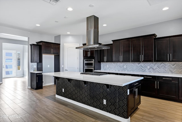 kitchen with island exhaust hood, a kitchen breakfast bar, a center island, and stainless steel appliances