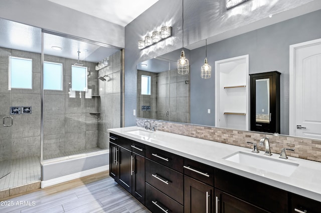 bathroom featuring decorative backsplash, an enclosed shower, plenty of natural light, and vanity