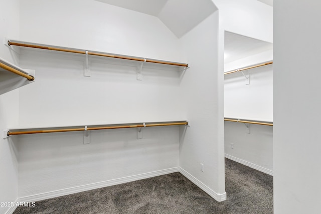 spacious closet featuring lofted ceiling and dark colored carpet