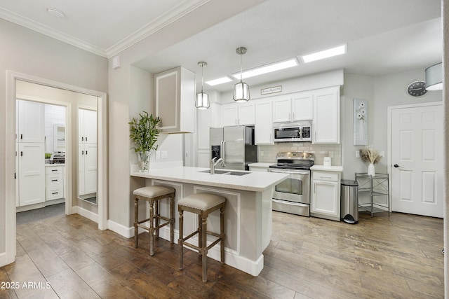 kitchen with a peninsula, stainless steel appliances, a kitchen bar, and hardwood / wood-style flooring