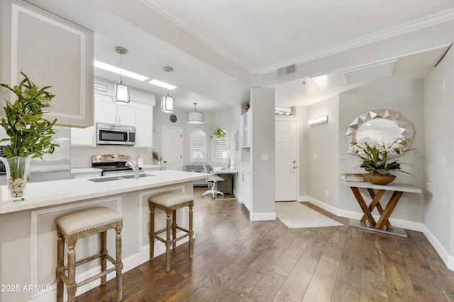 kitchen featuring dark wood-style floors, a sink, stainless steel appliances, a kitchen breakfast bar, and tasteful backsplash