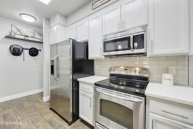 kitchen featuring light wood finished floors, backsplash, baseboards, appliances with stainless steel finishes, and white cabinets