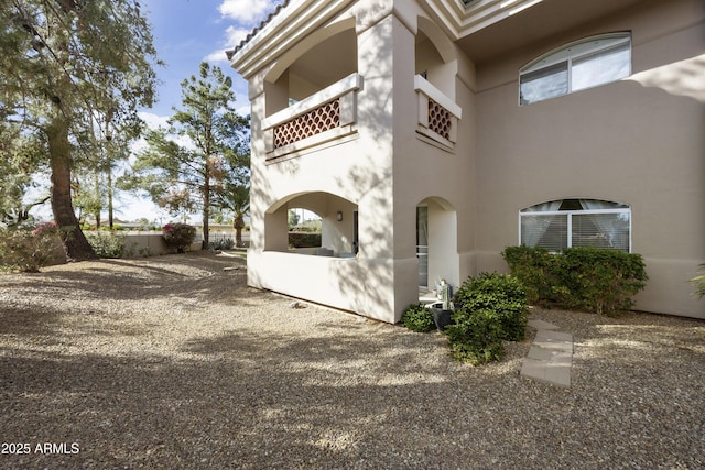 view of side of home featuring stucco siding, a balcony, and central AC