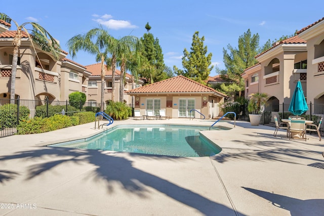 community pool featuring a patio, fence, and a residential view