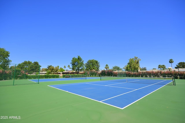 view of tennis court with community basketball court and fence