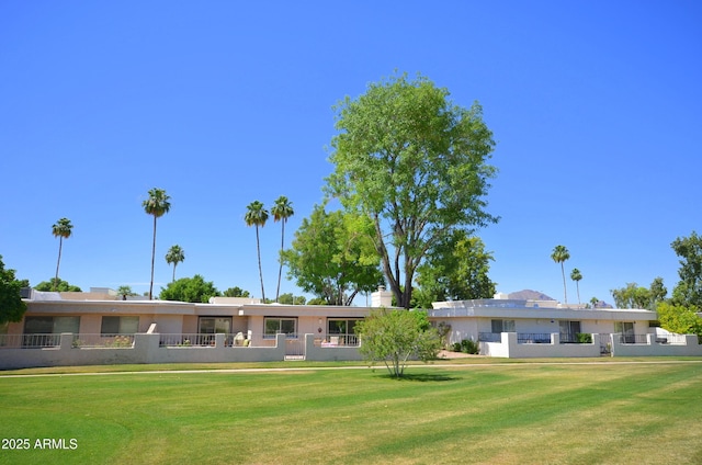 back of property featuring a fenced front yard and a lawn