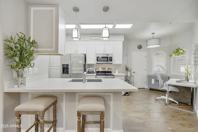 kitchen featuring a breakfast bar, a sink, backsplash, stainless steel appliances, and a peninsula