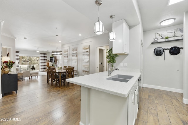 kitchen with baseboards, pendant lighting, hardwood / wood-style flooring, white cabinetry, and a sink