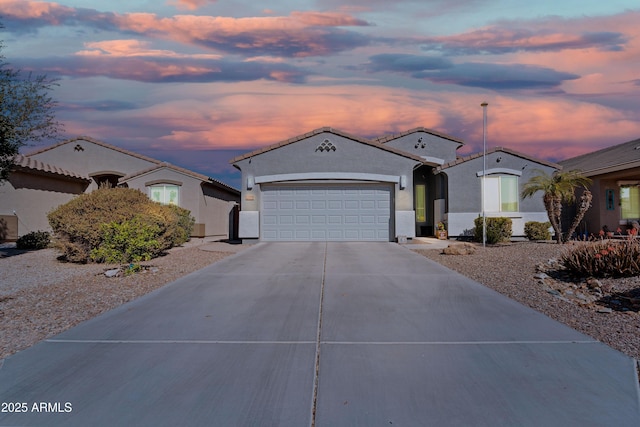 mediterranean / spanish-style house featuring a garage, concrete driveway, and stucco siding