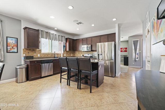 kitchen with stainless steel appliances, visible vents, backsplash, and dark brown cabinets