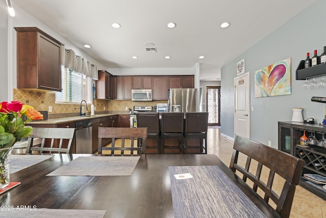 kitchen featuring dark brown cabinetry, baseboards, visible vents, decorative backsplash, and stainless steel appliances