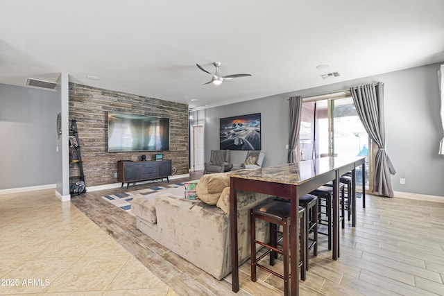 living room featuring a ceiling fan, light wood-style floors, visible vents, and baseboards