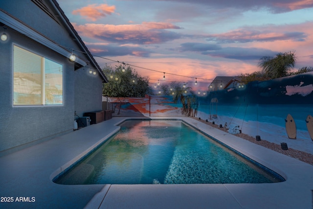 pool at dusk with a fenced backyard and a fenced in pool