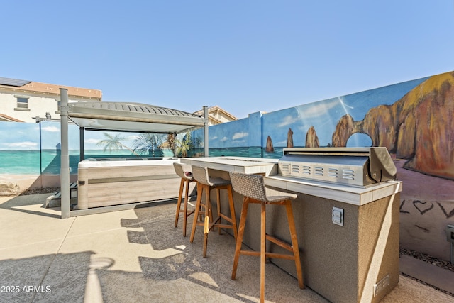 view of patio / terrace featuring an outdoor kitchen, fence, outdoor wet bar, and a hot tub