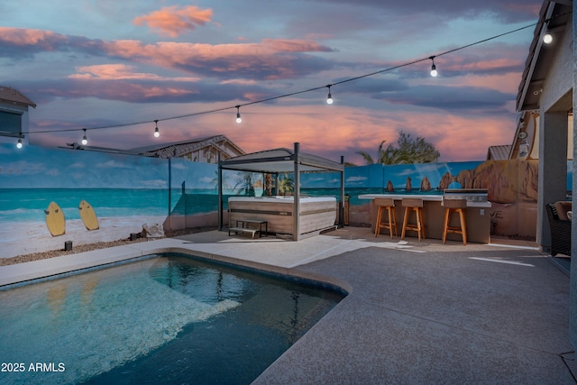 pool at dusk featuring a fenced in pool, a patio, outdoor dry bar, a hot tub, and a fenced backyard