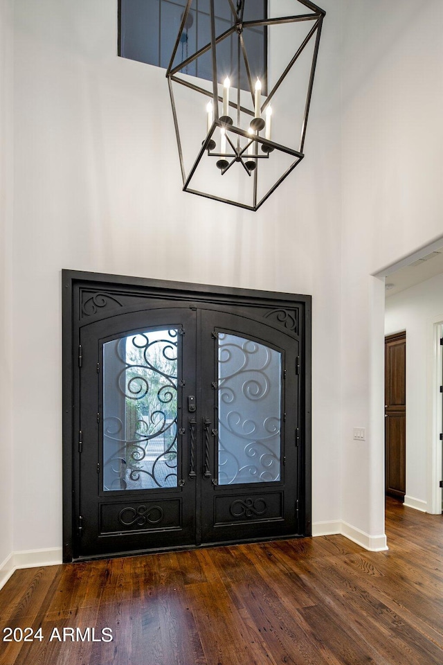 foyer entrance featuring a notable chandelier, dark wood-type flooring, and french doors