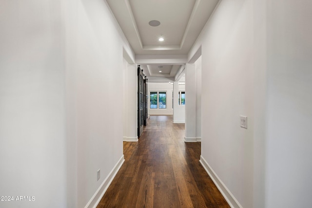 corridor with a raised ceiling and dark wood-type flooring