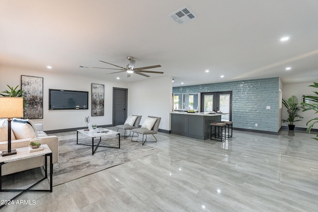 living room with ceiling fan, light tile patterned flooring, french doors, and brick wall