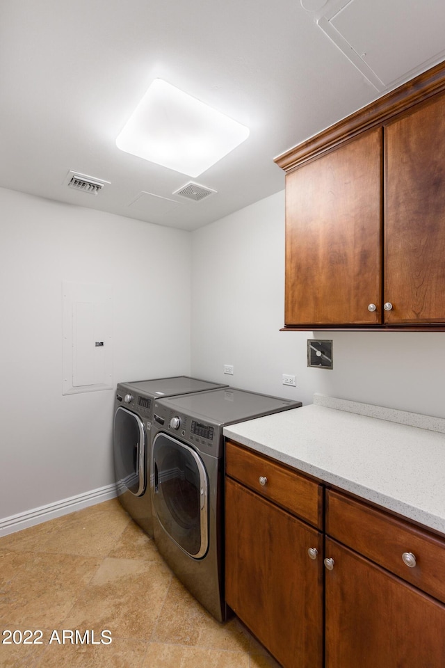 laundry area featuring washer and clothes dryer, electric panel, and cabinets