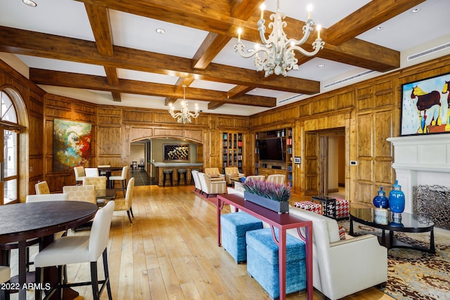 living room with beam ceiling, coffered ceiling, a chandelier, and wood walls