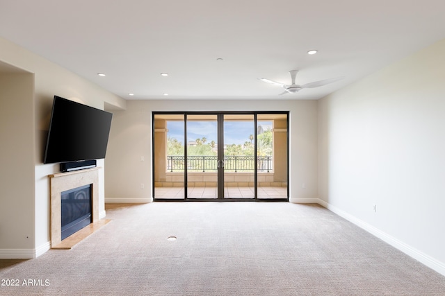 unfurnished living room featuring a fireplace, light colored carpet, and ceiling fan