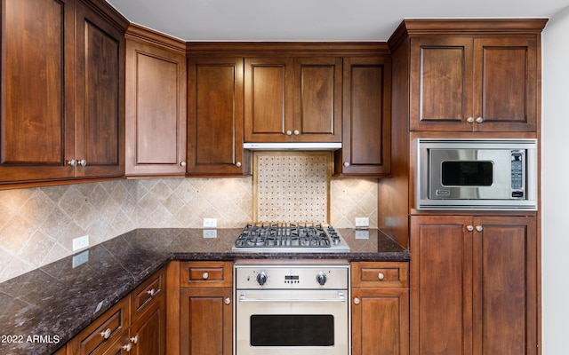 kitchen featuring stainless steel appliances, decorative backsplash, and dark stone counters