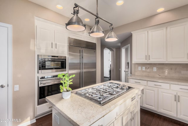 kitchen with decorative light fixtures, a center island, white cabinets, and appliances with stainless steel finishes