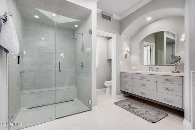 bathroom with a shower with door, vanity, ornamental molding, and toilet