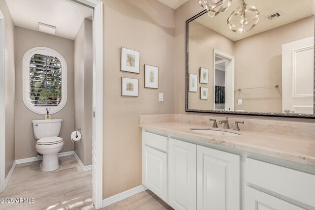 bathroom with vanity, toilet, and an inviting chandelier