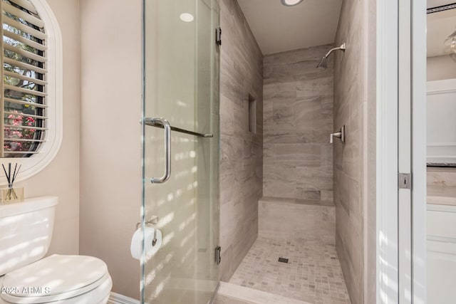 bathroom featuring a shower with door and toilet