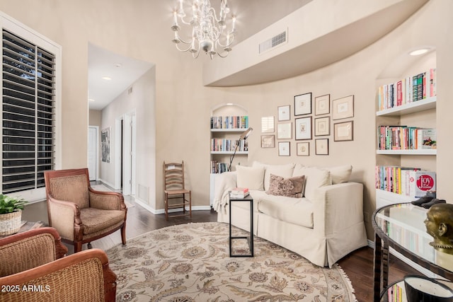 sitting room featuring an inviting chandelier, dark hardwood / wood-style flooring, and built in features