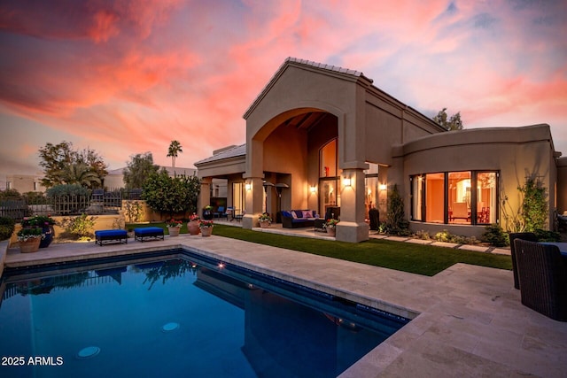 back house at dusk with a fenced in pool, outdoor lounge area, and a patio