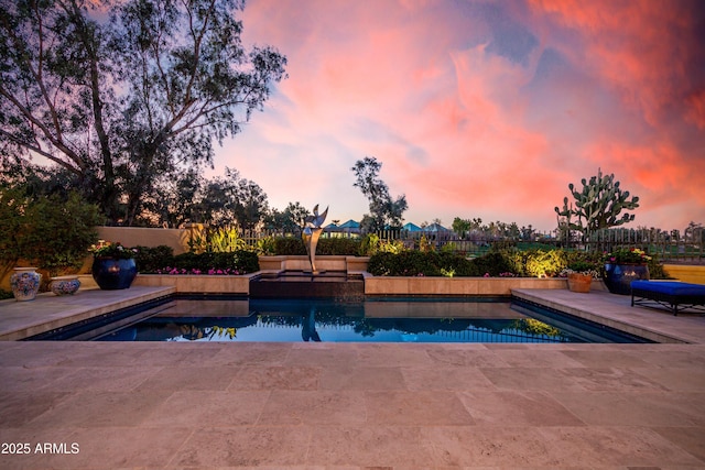 pool at dusk featuring a patio area